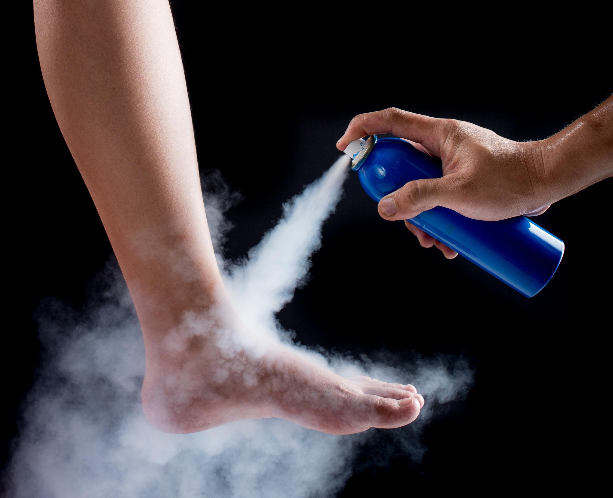 close-up-hand-spraying-medicine-leg-black-background